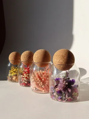 כלי זכוכית מעוצבים ומלאים בקוקטייל פרחים יבשים טבעיים, פקק שעם כדורי.
