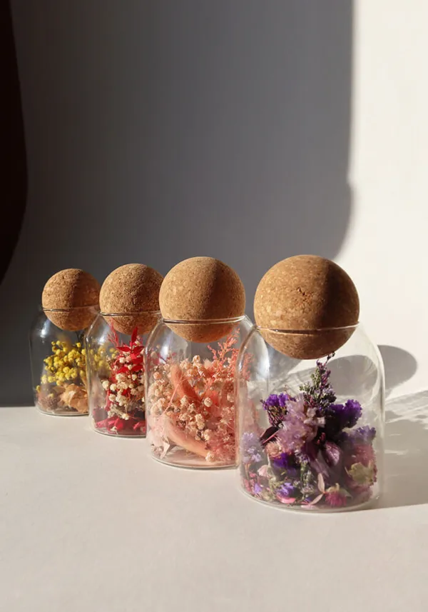 כלי זכוכית מעוצבים ומלאים בקוקטייל פרחים יבשים טבעיים, פקק שעם כדורי.